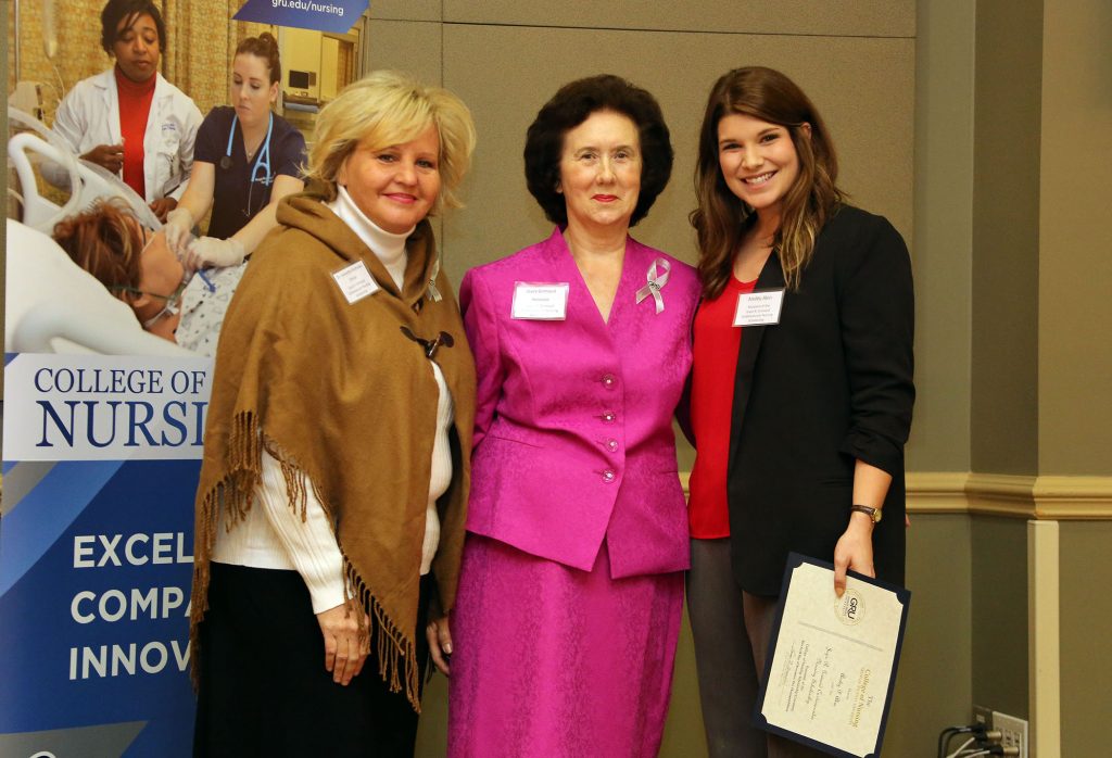 Three women stand side-by-side in a large banquet room.