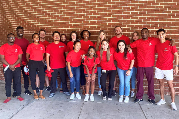 group of young adults in matching shirts standing in front of a wall