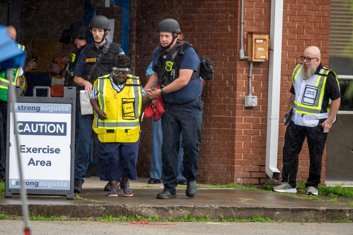 Emergency personnel escort an actor portraying a victim out of a school