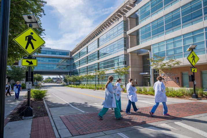 People in white coats walking across college campus