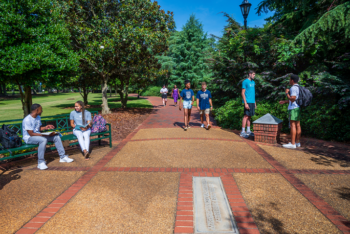 Augusta University students sitting and walking along the History Walk on the Summerville Campus.
