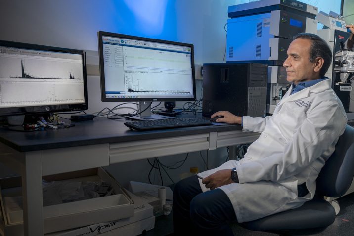 Man in white coat sits at computer