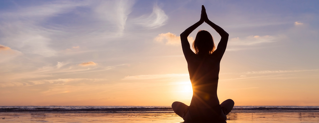 backside of woman doing yoga on the beach