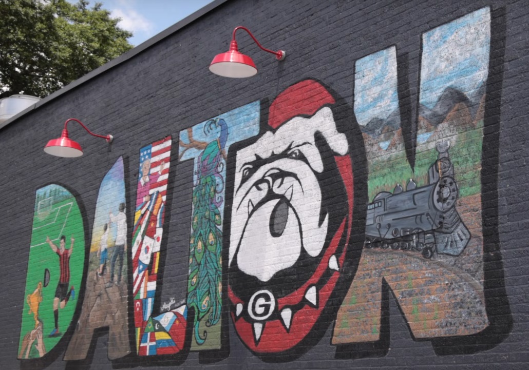 Dalton, GA painted on a wall. Each Letter is painted as something that represents a part of Dalton, GA