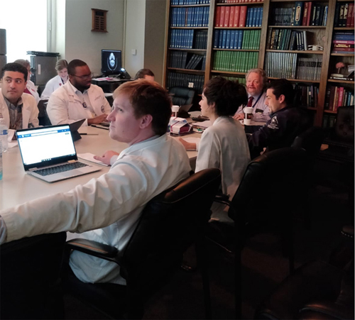 Residents sitting around a conference table with their laptops open. 