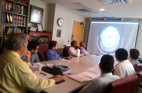 Residents sitting in class looking at a screen with an image of a brain scan in front of them