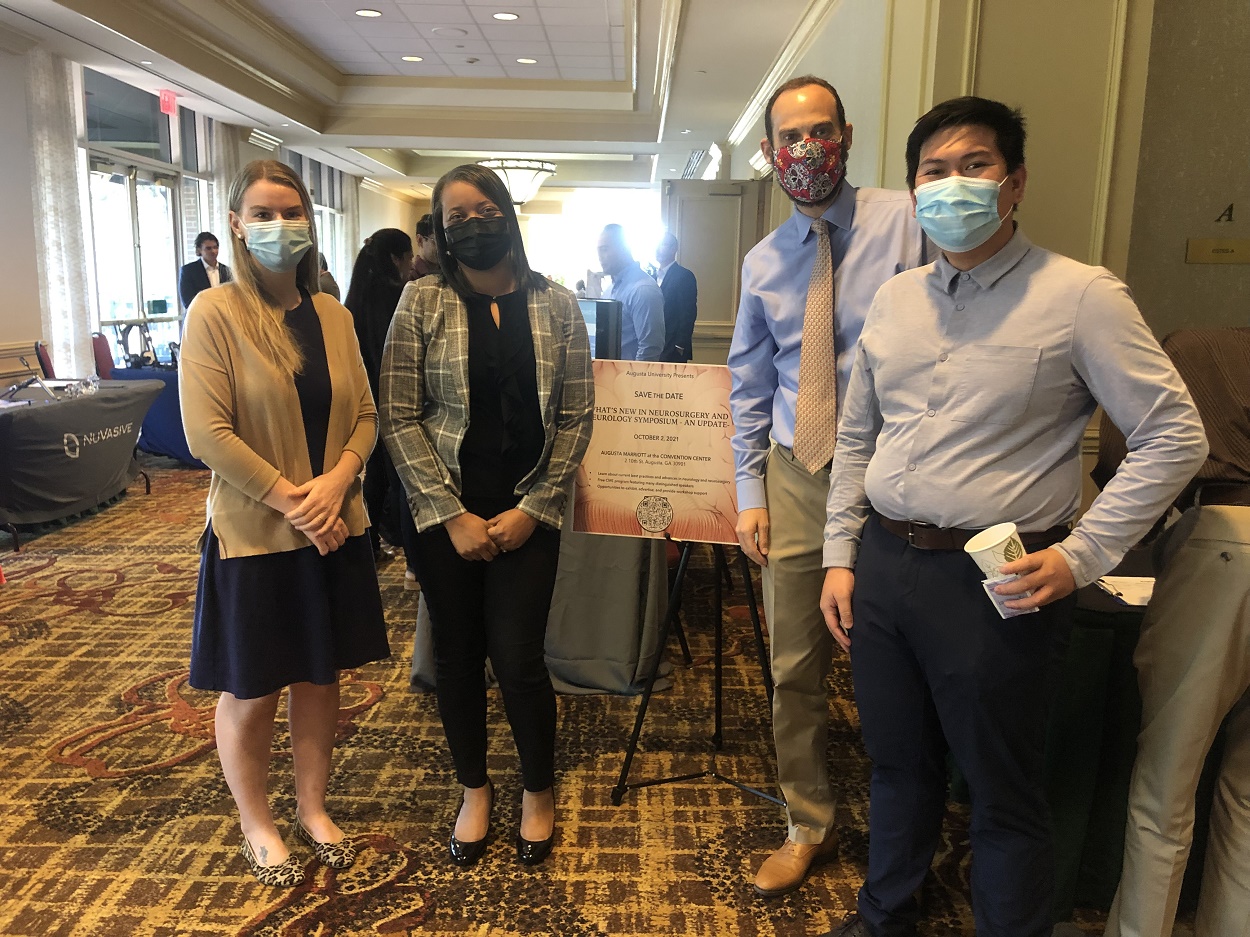 Dr. Switzer standing in a convention center hallway with 2 women and 1 man resident 