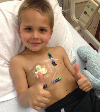 Young patient smiles and does double thumbs up to camera
