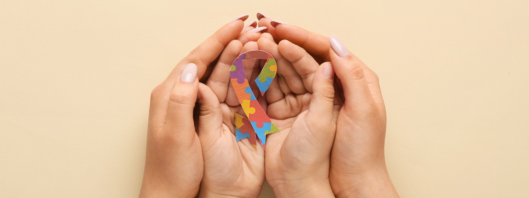 mother holding child's hands with autism awareness ribbon