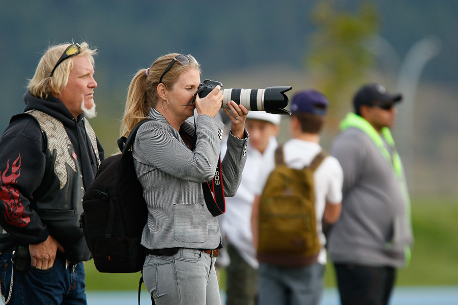 Sports photography - Woman with a large camera lens taking a photo at a sports venue
