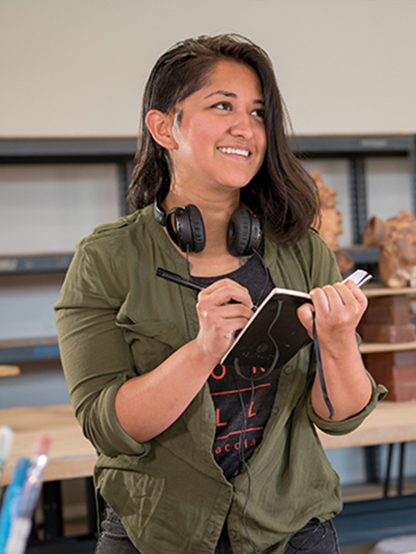 Art student holds sketchbook in classroom