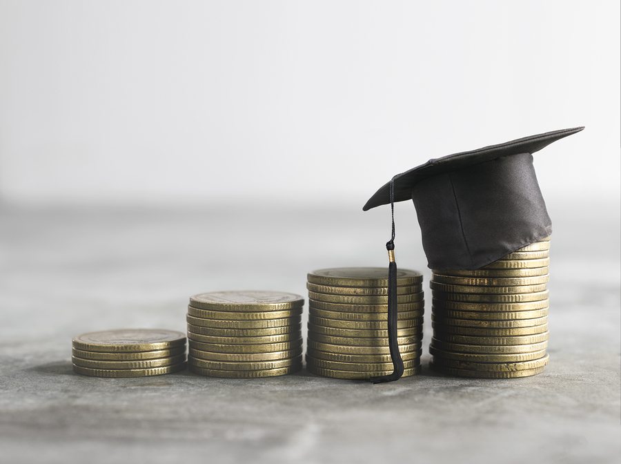 Stacks of coins with a graduation cap sitting on top of the last stack