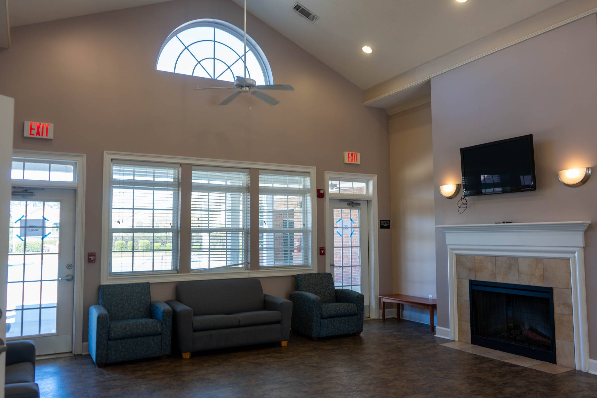Student common area showing couches, television, large windows and fireplace.