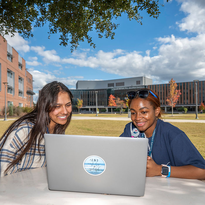 Two Female Students sitting with a laptop between them