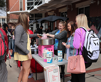 Students using a cotton candy machine at an outdoor campus event