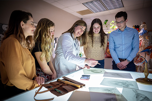 Medical illustration students and professor looking over work on a light table